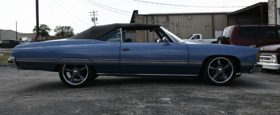A blue car with a black top is parked in a parking lot