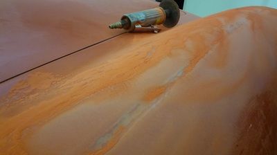 A person is using a grinder on a piece of wood