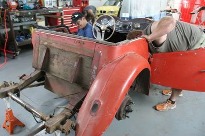 A man is working on a red car in a garage