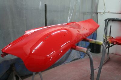 A red car is being painted in a garage