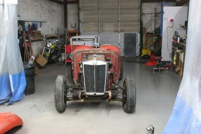 An old red car is sitting in a garage.