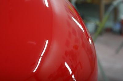 A close up of a red vase with a plant in the background