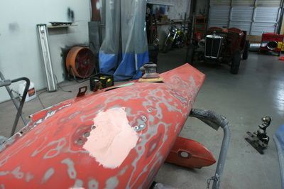A red boat is being painted in a garage