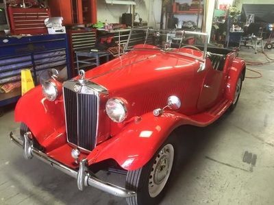 A red vintage car is parked in a garage