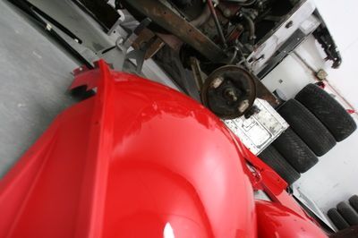 A red car is being worked on in a garage