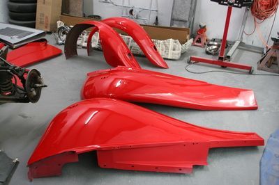 A bunch of red fenders are sitting on the floor