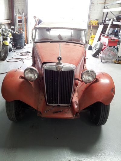 A red car is parked in a garage next to a motorcycle