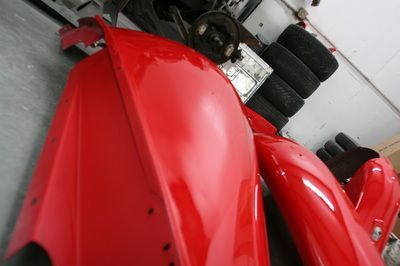 A bunch of red fenders are sitting in a garage