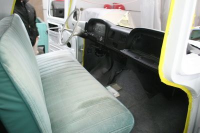 The interior of a white truck with green seats and yellow tri