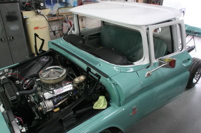 A blue truck with the hood open is sitting in a garage