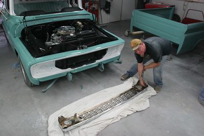 A man is working on the front bumper of a car