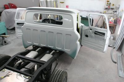 A truck is being built in a garage with the doors open