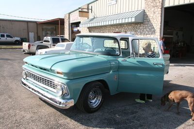 A blue truck is parked in front of a building with its doors open