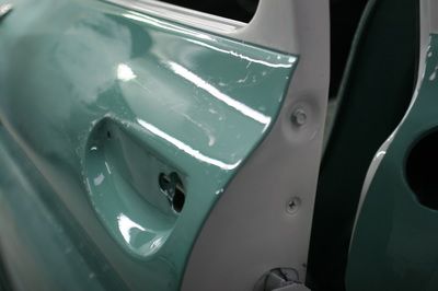 A close up of a green car door with a white trim