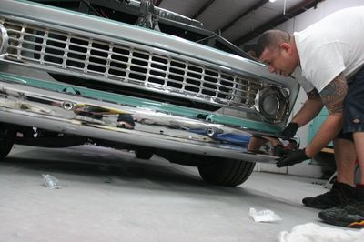 A man is working on the front bumper of a truck