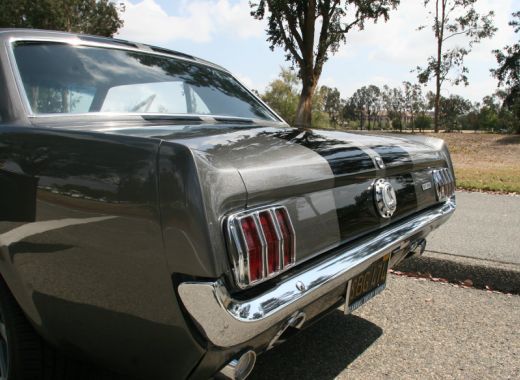A black mustang is parked on the side of the road