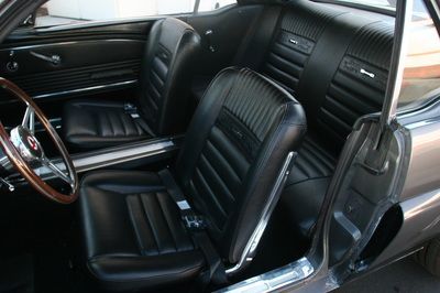The inside of a car with black leather seats and a wooden steering wheel