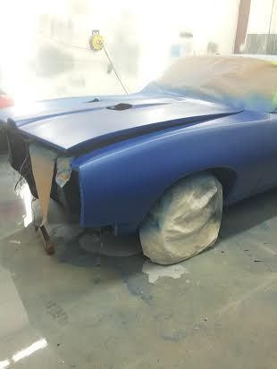 A blue car is sitting in a garage covered in plastic