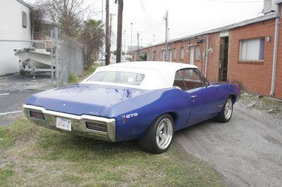 A blue car with a white top is parked in front of a brick building
