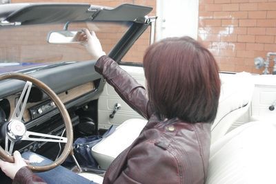 A woman in a leather jacket is driving a car
