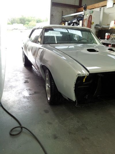 A white car is parked in a garage with the hood up