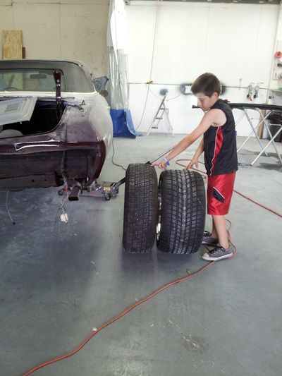 A young boy is pushing two tires in a garage