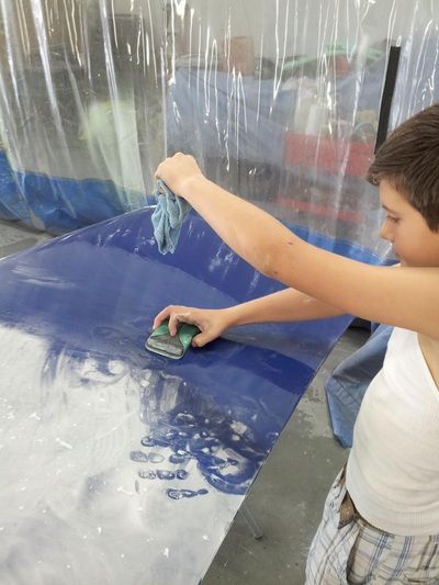 A young boy is cleaning a blue surface with a sponge