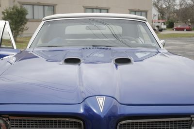 A blue pontiac convertible is parked in a parking lot