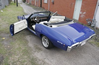 A blue gto convertible with its doors open