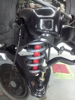 A close up of a suspension system on a car in a garage