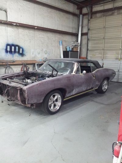 A purple car is parked in a garage with the hood up