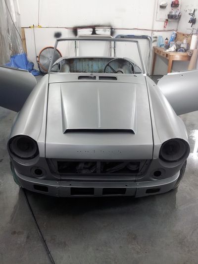 A silver car is sitting in a garage with its doors open