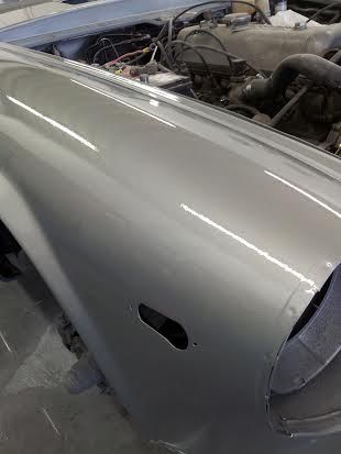 A silver car with the hood open is sitting in a garage