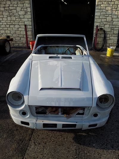 A white car is parked in front of a brick building