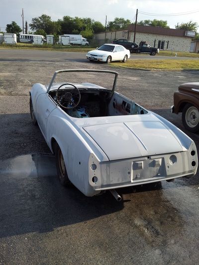 A white convertible car is parked in a parking lot