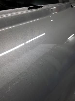 A close up of a silver car door in a garage