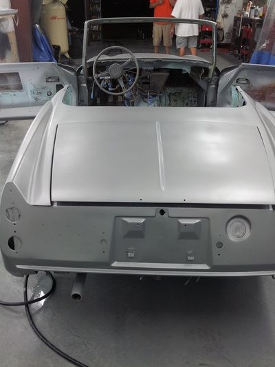 A silver car is being built in a garage