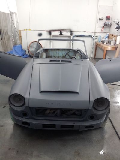 A grey car with its doors open in a garage