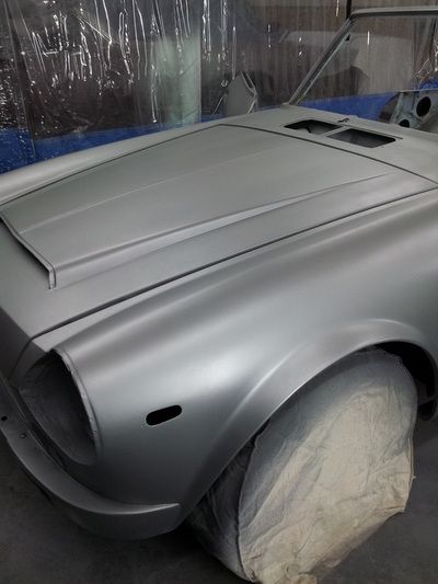 A silver car is sitting in a garage with its hood open