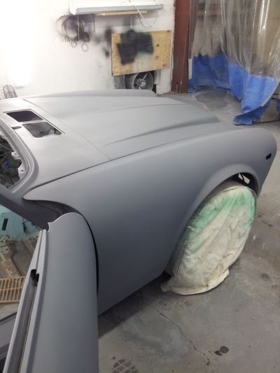 A car is being painted in a garage with the door open