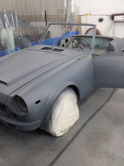 A grey car is sitting in a garage with its doors open