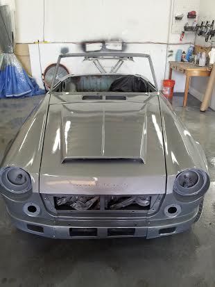 A silver car is parked in a garage with the hood up