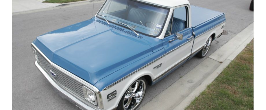 A blue and white truck is parked on the side of the road