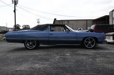 A blue convertible car is parked in a parking lot