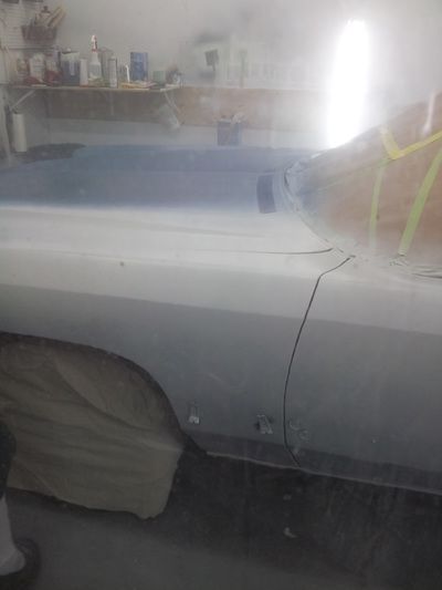 A white car is being painted in a garage