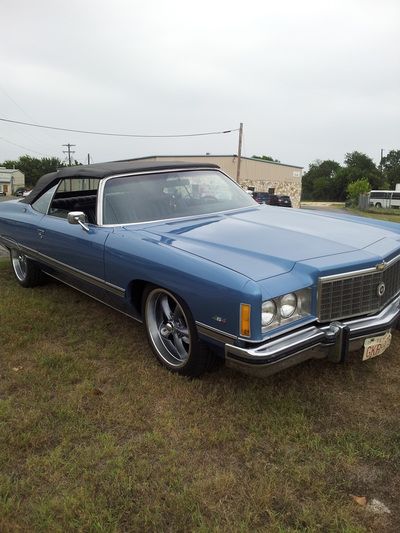 A blue car is parked in a grassy field