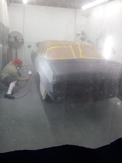 A man is spray painting a car in a garage