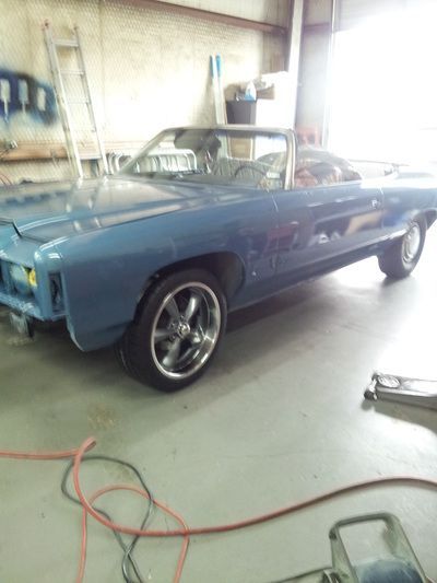 A blue car is parked in a garage next to a ladder