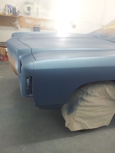 A blue car is sitting in a garage with a cover on it