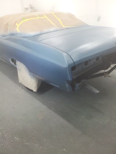 A blue car is sitting in a garage being painted